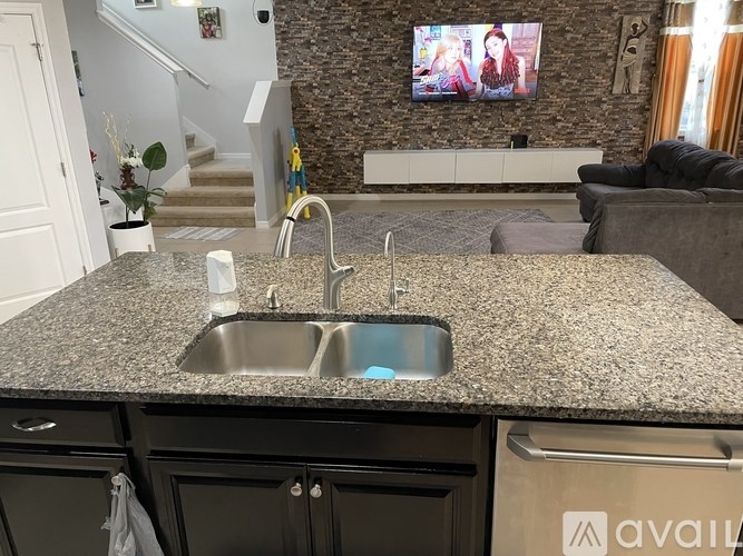 A kitchen with granite countertops and a TV mounted on the wall.