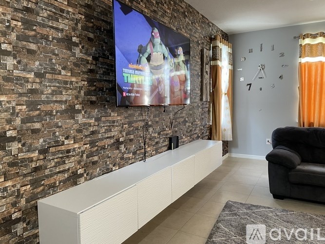 A living room with a flat screen TV mounted on a brick wall.