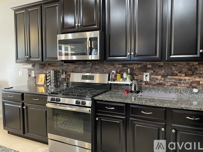 A kitchen with black cabinets and a stone backsplash.