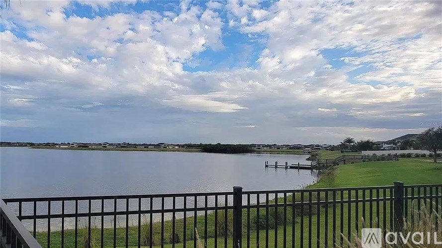 A view of a lake from a balcony with a black railing.