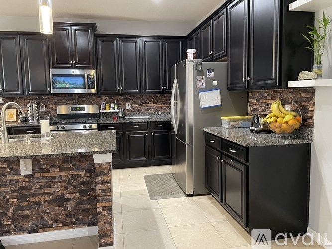A kitchen with black cabinets and a stone counter.