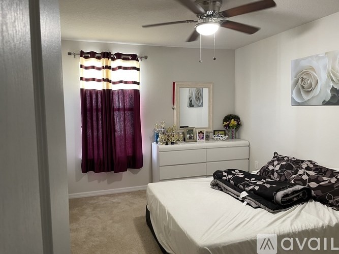 A bedroom with a bed, dresser, and a ceiling fan.