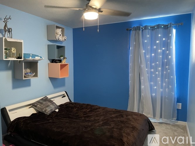 A bedroom with a bed, a ceiling fan, and a window with curtains.
