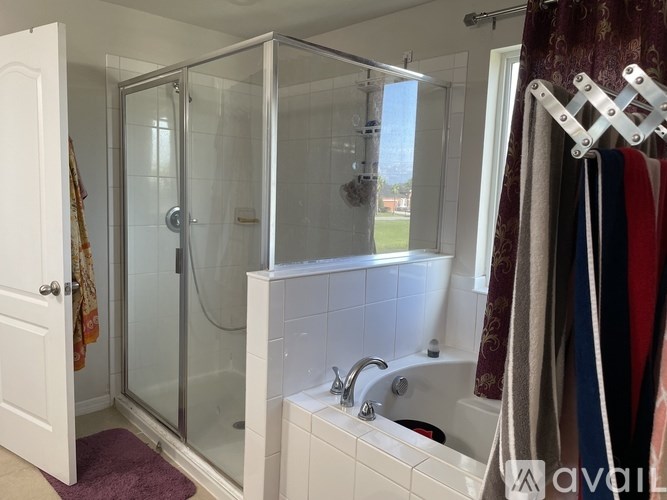 A white bathroom with a glass shower door and a white bathtub.