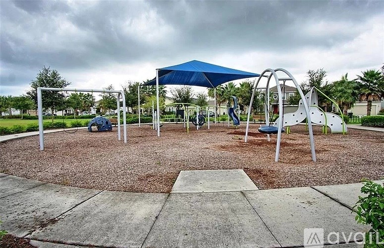 A playground with a blue canopy and a slide.