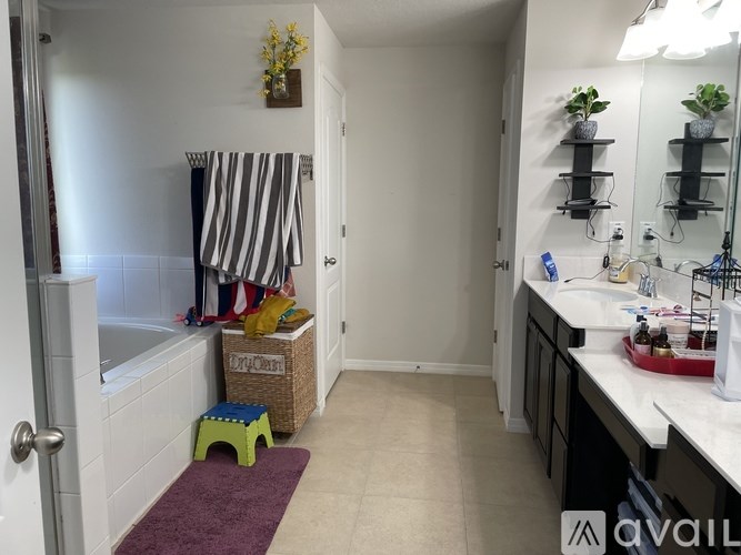A bathroom with a white tub, a purple rug, and a white sink.