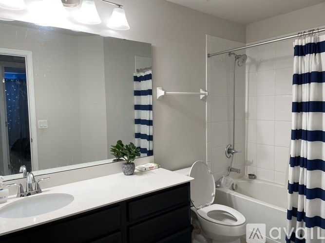 A bathroom with a white sink, toilet, and striped shower curtain.