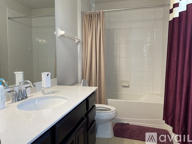 A bathroom with a white sink, toilet, and a red shower curtain.