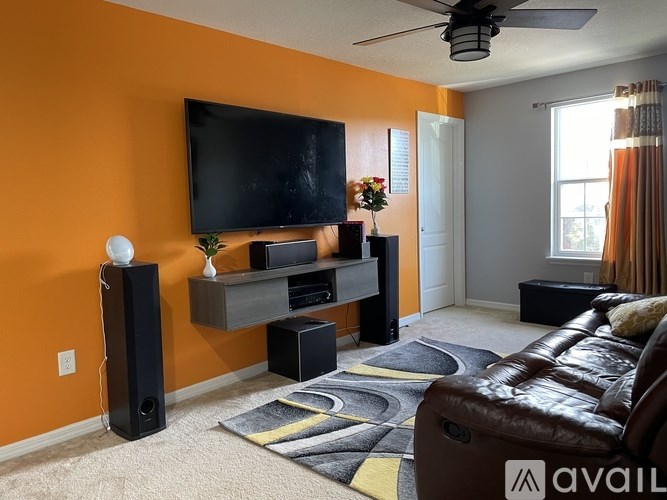 A living room with a brown leather couch and a flat screen TV mounted on the wall.