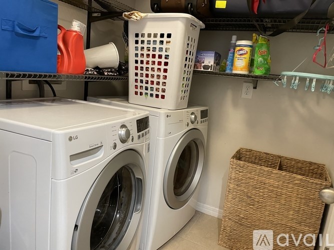A white LG washing machine sits on top of another white LG washing machine in a small laundry room.
