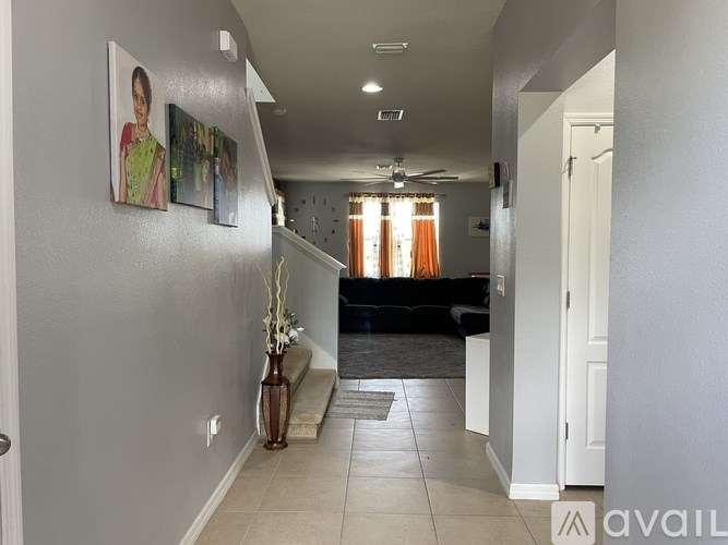 A hallway with a vase on the floor and pictures on the wall.