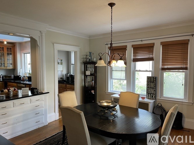 A dining room with a table and chairs and a sign on the window.