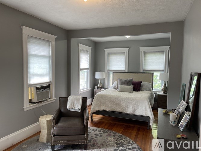 A bedroom with a bed, chair, and window.