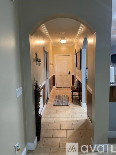 A hallway with a tiled floor and a white door.