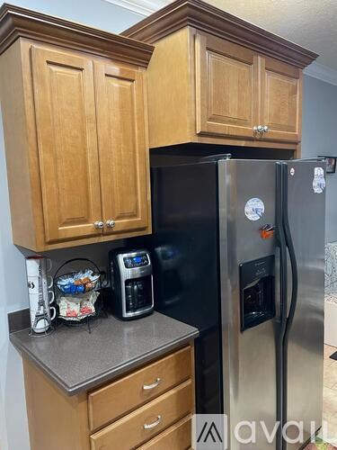 A kitchen with wooden cabinets and a black refrigerator.