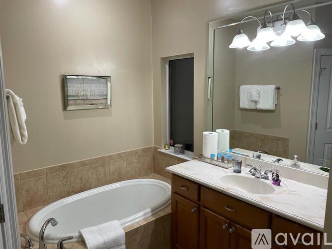 A bathroom with a tub, sink, mirror, and towel rack.