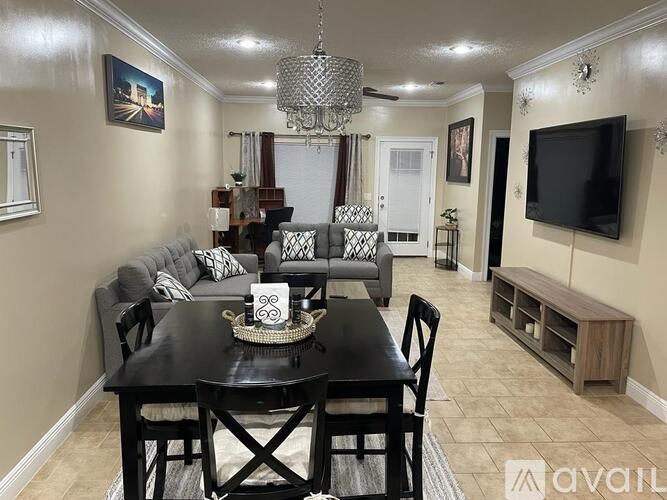 A black dining table with a bowl on it and a grey couch with pillows.
