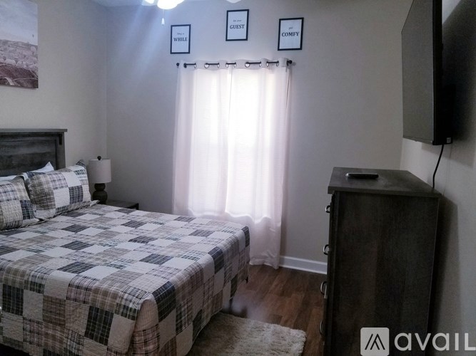 A bedroom with a bed, a dresser, and a window with curtains.