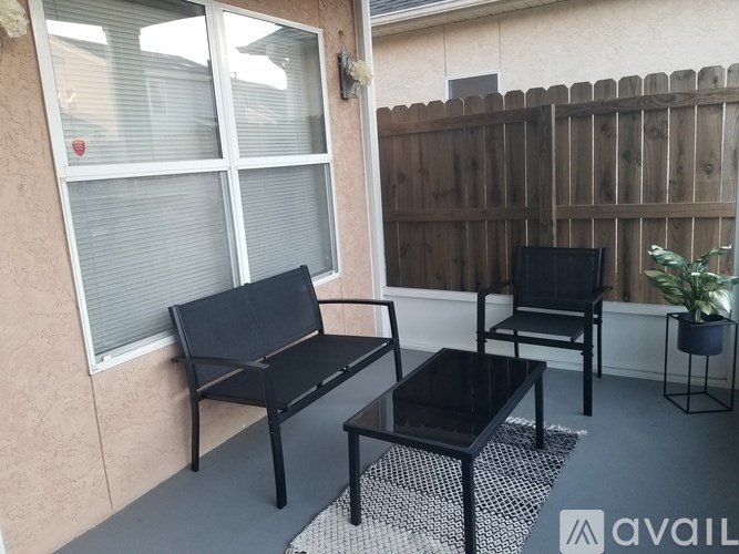 A patio with a black table and two black chairs.