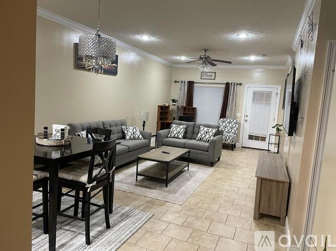 A living room with a grey couch, a black dining table, and a ceiling fan.