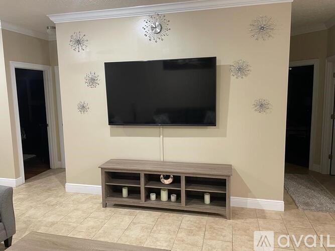 A living room with a flat screen TV mounted on the wall above a wooden entertainment center.