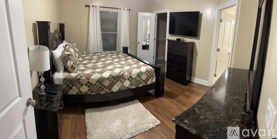 A bedroom with a bed, dresser, and television.