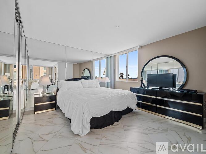A bedroom with a large bed, a TV, and a mirror on the wall.