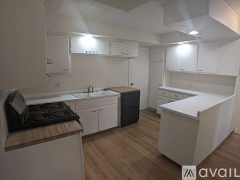 A kitchen with white cabinets and a wooden counter top.