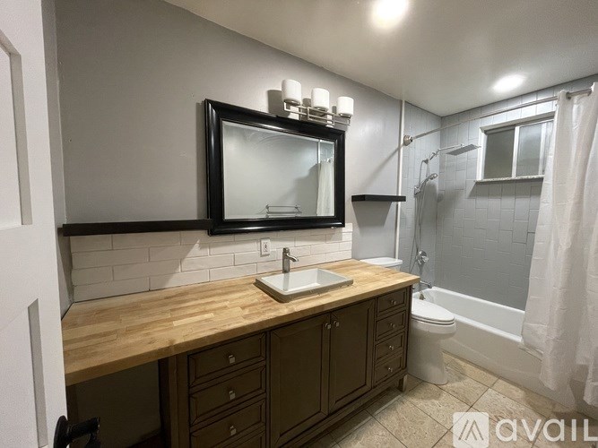 A bathroom with a wooden countertop and a large mirror above it.