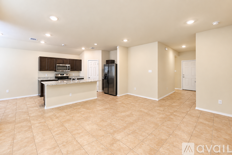 A spacious living room with a kitchenette and a black refrigerator.