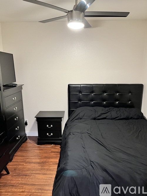 A bedroom with a black bed, a black dresser, and a black nightstand.