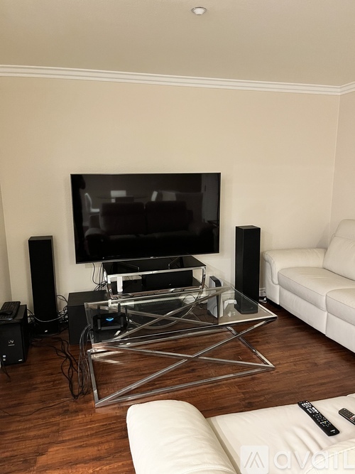 A modern living room with a television, speaker, and glass coffee table.