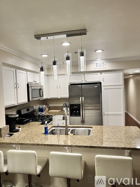 A kitchen with granite countertops and white chairs.