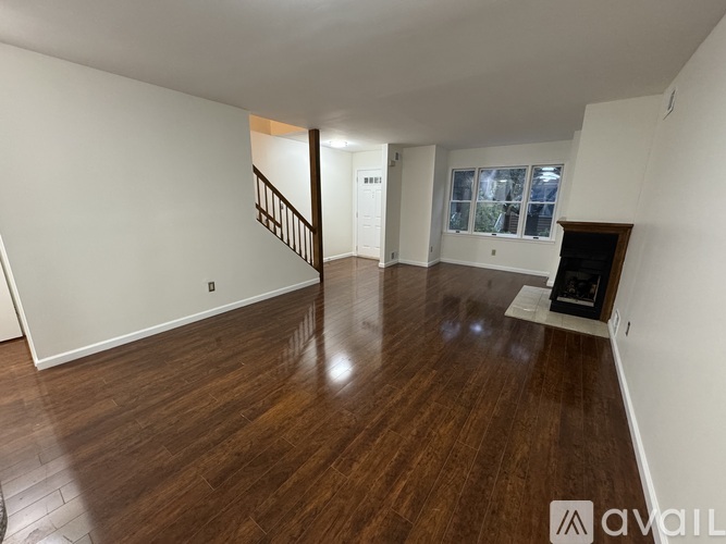 A spacious living room with hardwood floors and white walls.