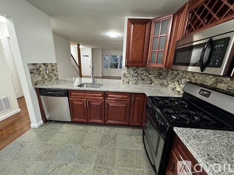 A kitchen with a black stove top oven and a black microwave above it.