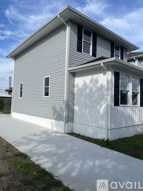 A house with a grey siding and white trim is shown.