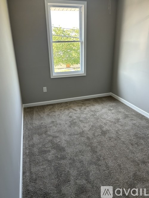 A room with a carpeted floor and a window.