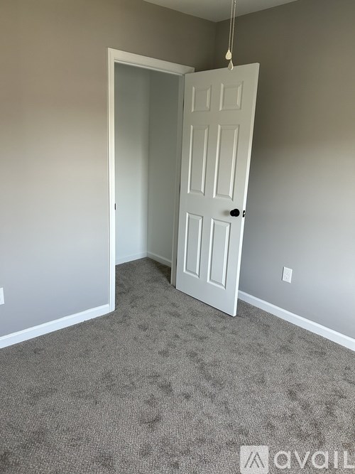 A room with a white door and carpeted floor.