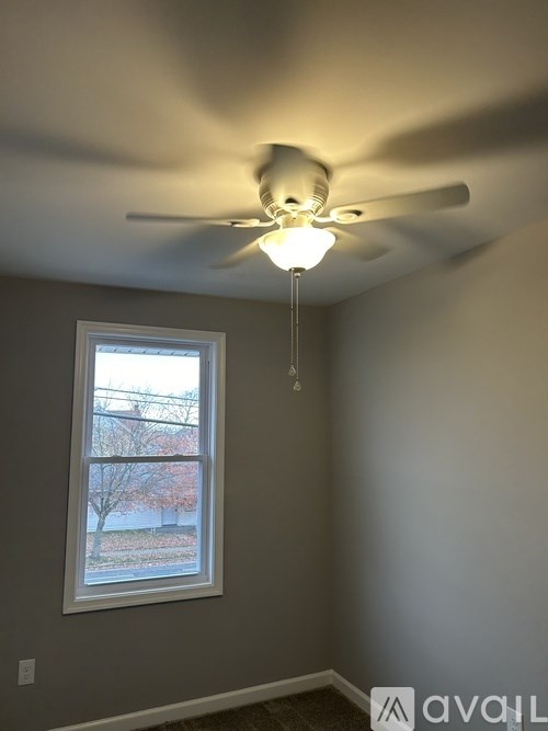 A room with a ceiling fan and a window.