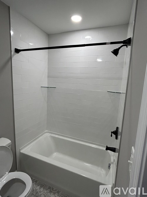 A white tiled bathroom with a toilet and a bathtub.