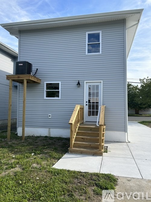 A house with a grey siding and a wooden staircase leading to the front door.