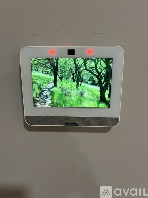 A small white device with a screen displaying a forest scene and two red lights on top.