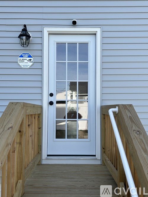 A white door with a glass window is on a wooden deck.