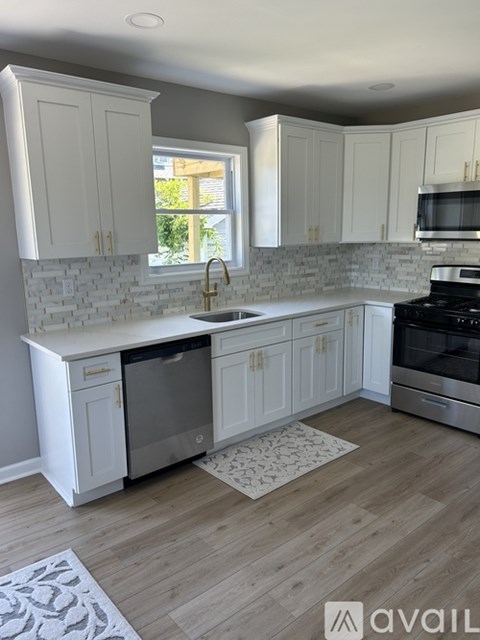 A kitchen with white cabinets and a wooden floor.
