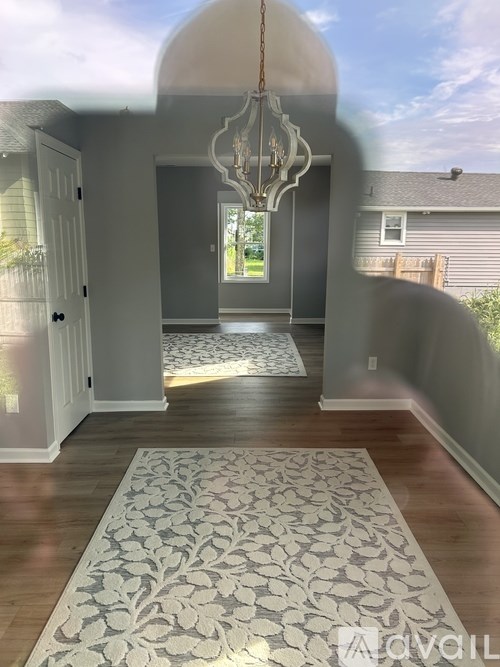A room with a chandelier and a patterned rug.