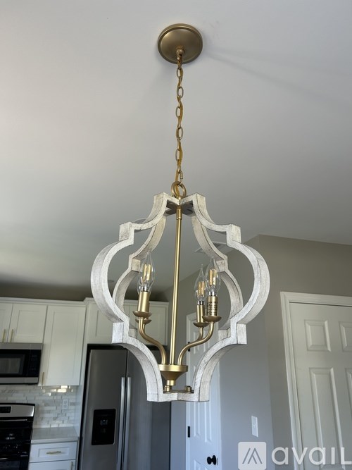 A chandelier with a white and gold design hangs from a chain.