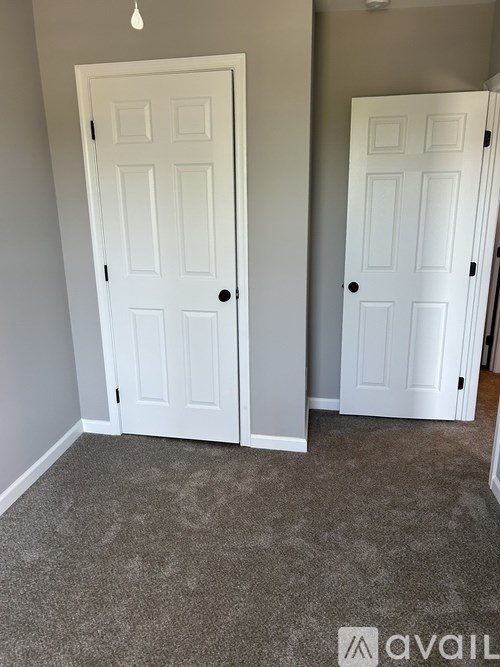 Two white doors in a room with carpeted floor.