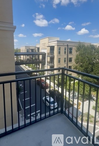 A balcony with a black railing and a person sitting on a chair.