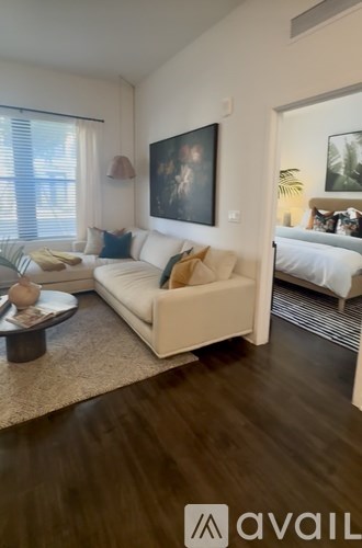 A living room with a white sofa and a painting on the wall.