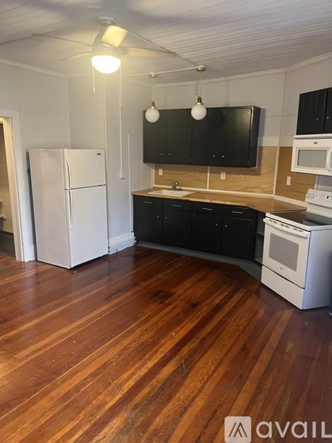 A kitchen with a white refrigerator and black cabinets.